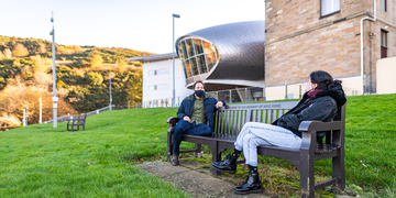 Students with masks sitting socially distanced on bench outside Craiglockhart campus