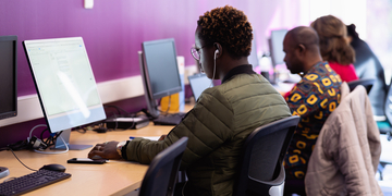 Three students sitting at a row of computers
