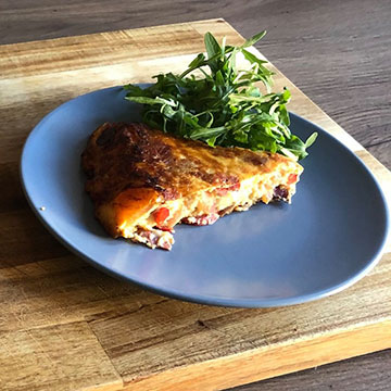 Slice of frittata on plate with salad