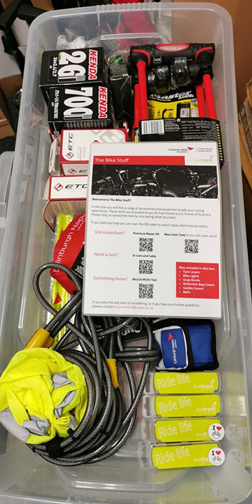 Box with a selection of cycling resources, including bike pumps and reflector bands