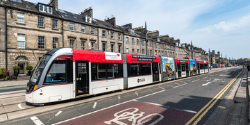 Tram travelling along Edinburgh city centre next to road and cycle lane