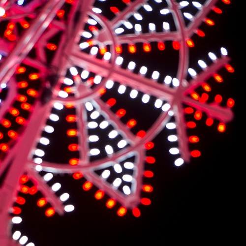 Red and white festive lights in the shape of a snowflake against a black night sky