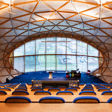 Interior of Lindsay Stewart lecture theatre, looking from the seating down to the windows and podium at the front