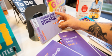 Close-up of student holding a dyslexia leaflet on a self-help display