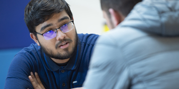 A student sitting in conversation with someone else, a coffee cup in the foreground