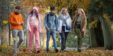 A group of students on a relaxing autumn walk together, with trees and leaves