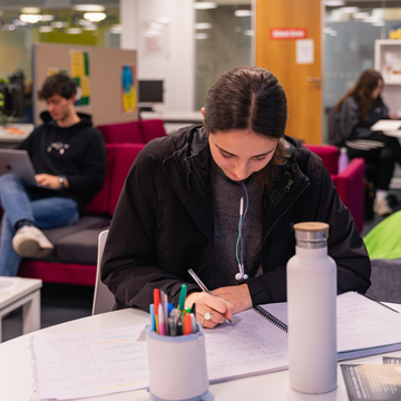 A student sitting in a study space, working with a notepad