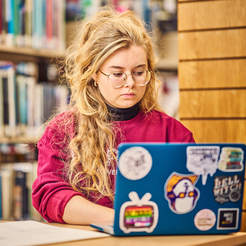 A student sitting in a study space, working on a laptop