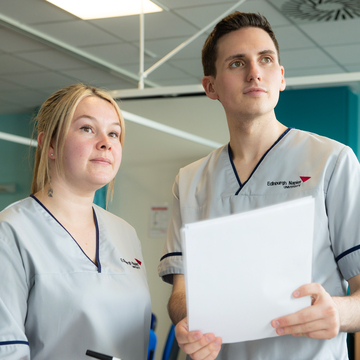 Two nursing students, standing holding notes