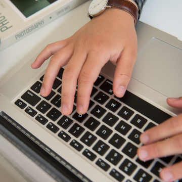 Student typing on laptop keyboard