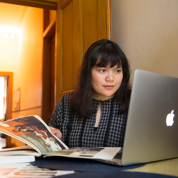 Student at home with magazine and laptop