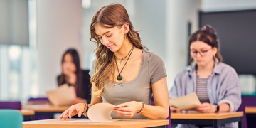 Students sitting in an examination room, looking at their papers