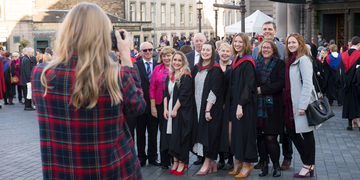 A group of students and their families having their photograph taken in their graduation gowns